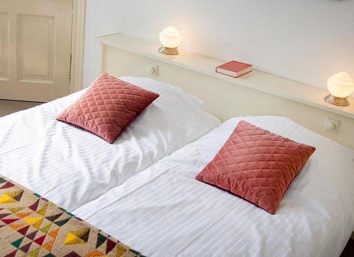 Zithoek met glas-in-lood ramen in B&B De Postoari Terschelling, Hoorn, biedt een sfeervolle plek om te ontspannen.