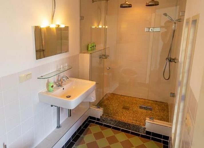 Zithoek met glas-in-lood ramen in B&B De Postoari Terschelling, Hoorn, biedt een sfeervolle plek om te ontspannen.