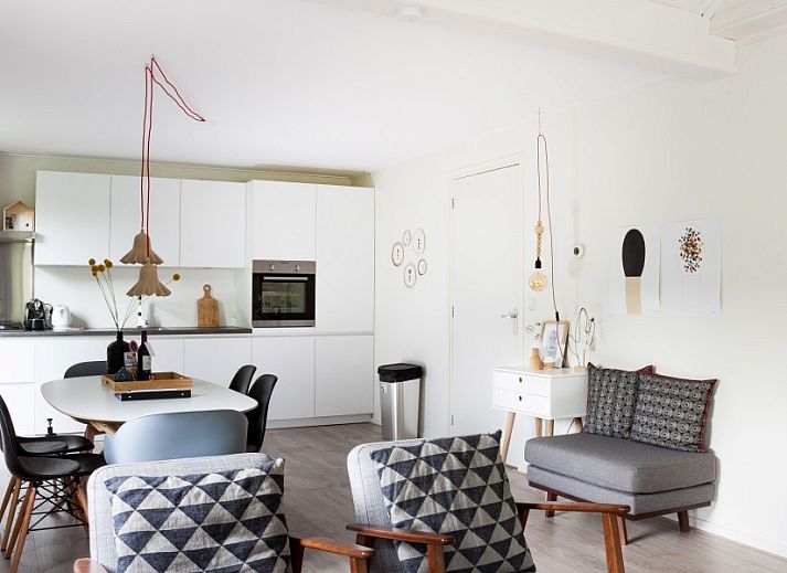 Ontspan op de ruime veranda van De Botter, een strandhuis in Makkum, met uitzicht op de groene omgeving.