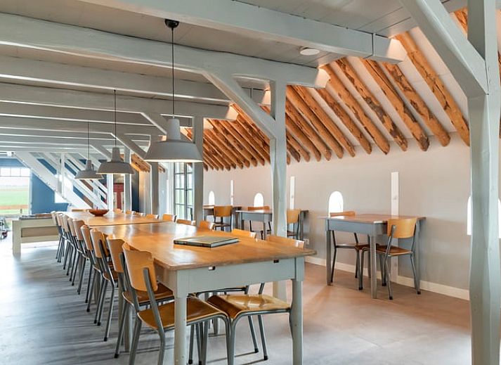 Grote eetzaal in Vakantiehuisje in Piaam met lange houten tafels, perfect voor groepsdiners aan de Friese meren.