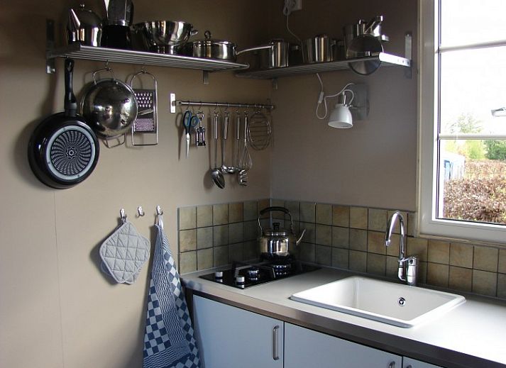 Gezellige binnenruimte van de lodge in Warns met houtkachel en eetruimte, nabij het IJsselmeer en de Friese meren.