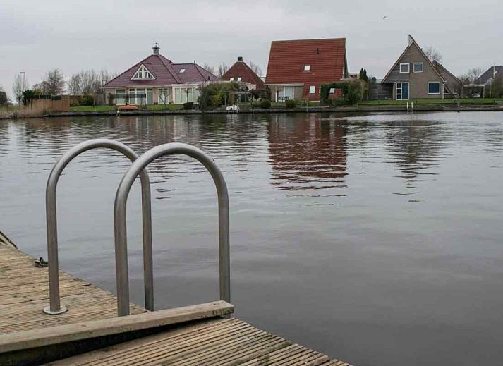 Luchtfoto van vakantiehuis FR061 in Koudum, gelegen aan de Friese meren, met rood dak en groene omgeving.