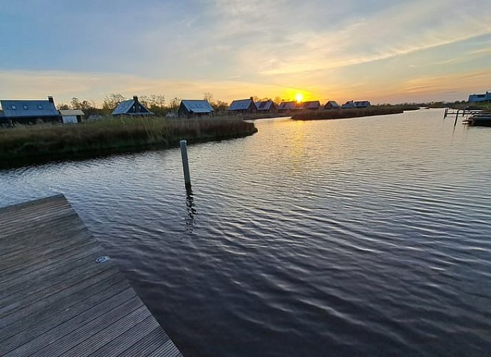 Huisje in Sint Nicolaasga met uitzicht op het water en houten steiger, gelegen bij de Friese meren.