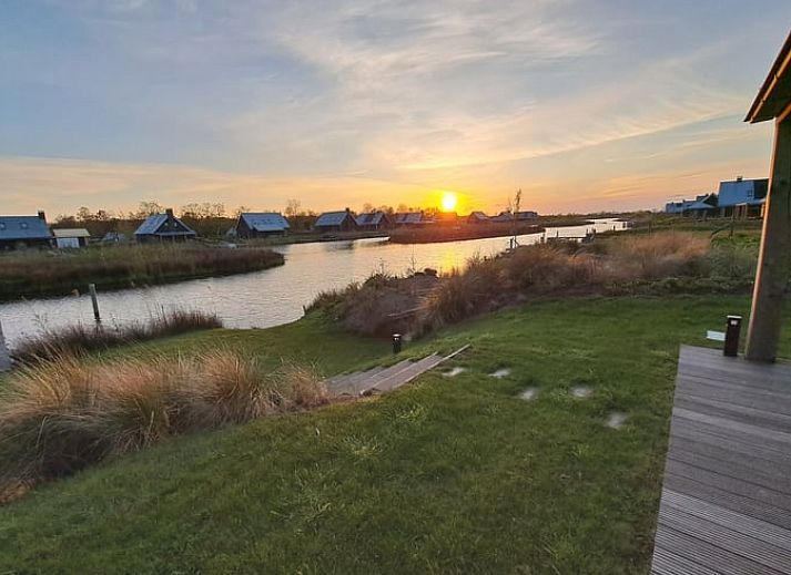 Huisje in Sint Nicolaasga met uitzicht op het water en houten steiger, gelegen bij de Friese meren.