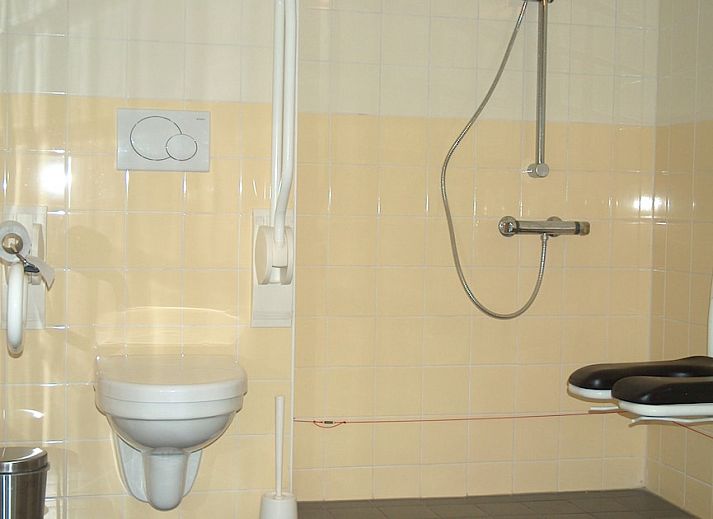 Gezellige binnenruimte van Mindervalide Havenappartement in Terherne, Sneekermeer, met comfortabele rode bank in het vakantiehuis.