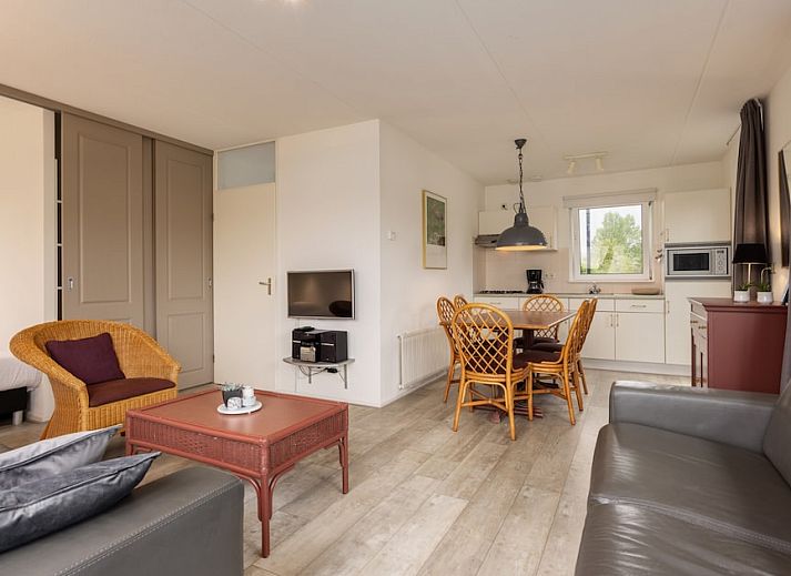 Spacious living room of Wetterbungalow 6 in Earnewald, Frisian Lakes, with comfortable seating area and views of the green surroundings.