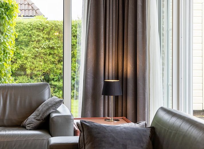 Spacious living room of Wetterbungalow 6 in Earnewald, Frisian Lakes, with comfortable seating area and views of the green surroundings.