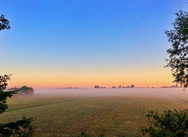 Atemberaubender Sonnenuntergang am Ferienhaus in De Veenhoop, der sich im Wasser der friesischen Seen spiegelt.