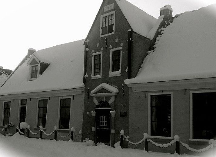 Gezellige woonkamer van De Thuiskamer, een vakantiehuis in Grou, Friesland, met comfortabele stoelen, open haard en een boekenkast.