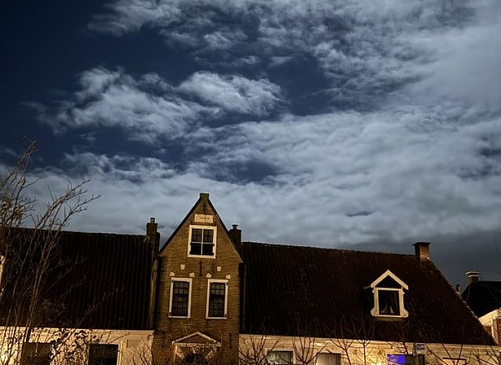 Gezellige woonkamer van De Thuiskamer, een vakantiehuis in Grou, Friesland, met comfortabele stoelen, open haard en een boekenkast.