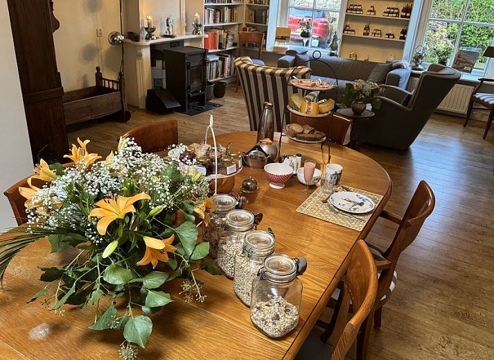 Gezellige woonkamer van De Thuiskamer, een vakantiehuis in Grou, Friesland, met comfortabele stoelen, open haard en een boekenkast.