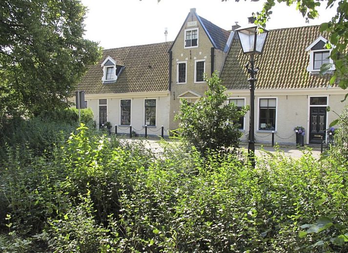 Gezellige woonkamer van De Thuiskamer, een vakantiehuis in Grou, Friesland, met comfortabele stoelen, open haard en een boekenkast.