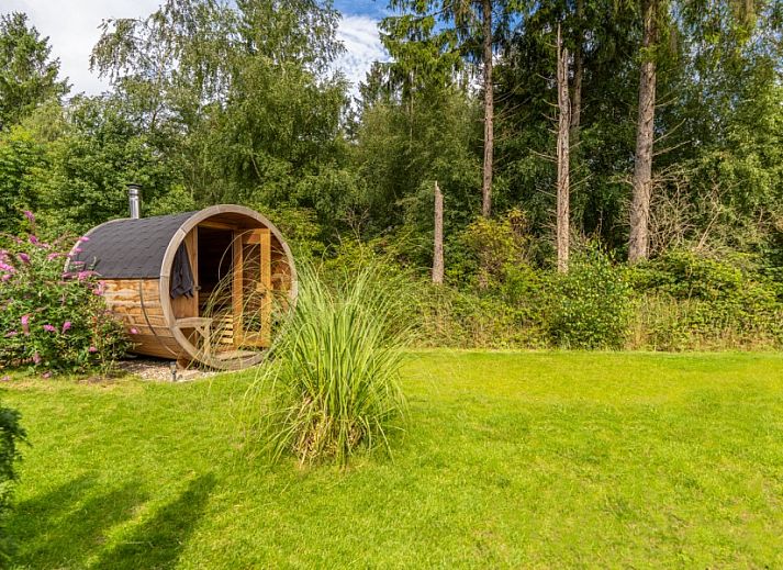 Gezellige woonkamer in De N8UIL vakantiehuis in Spier, Midden Drenthe, met een moderne haard en uitzicht op de natuur.