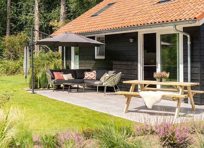 Gezellige woonkamer in De N8UIL vakantiehuis in Spier, Midden Drenthe, met een moderne haard en uitzicht op de natuur.