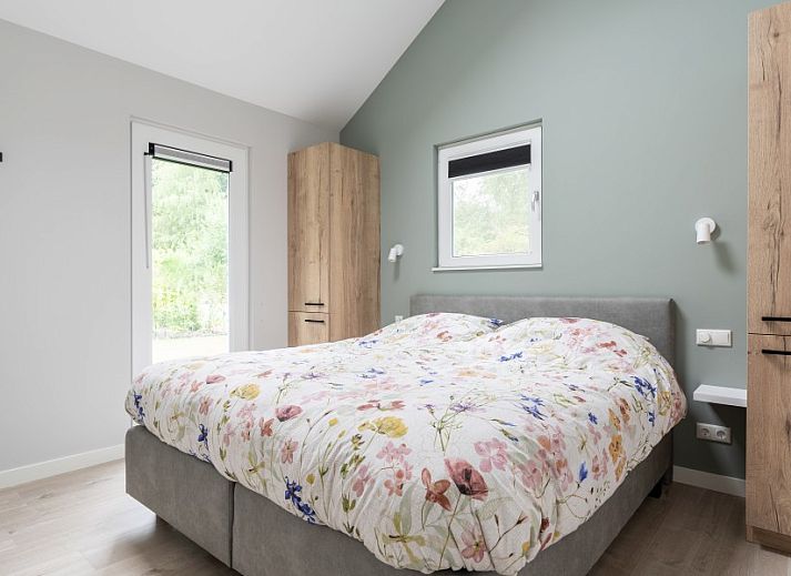 Gezellige woonkamer in De N8UIL vakantiehuis in Spier, Midden Drenthe, met een moderne haard en uitzicht op de natuur.