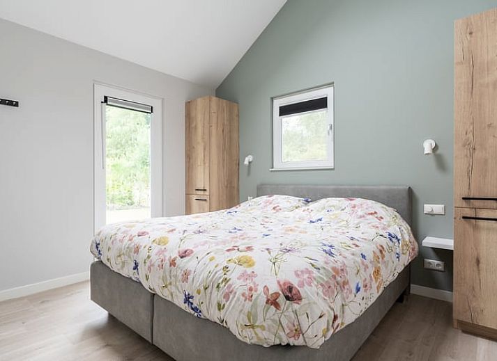 Vakantiehuisje in Spier, Drenthe, omringd door groene tuin en blauwe lucht.