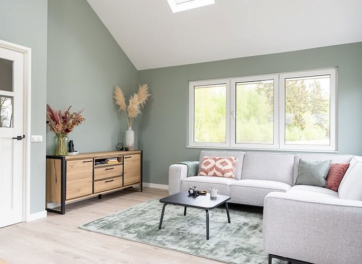 Vakantiehuisje in Spier, Drenthe, omringd door groene tuin en blauwe lucht.