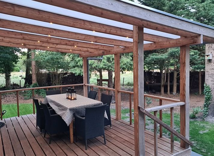 Rustic exterior of Cottage in Gasselte, Drenthe, surrounded by trees and a charming wooden fence.