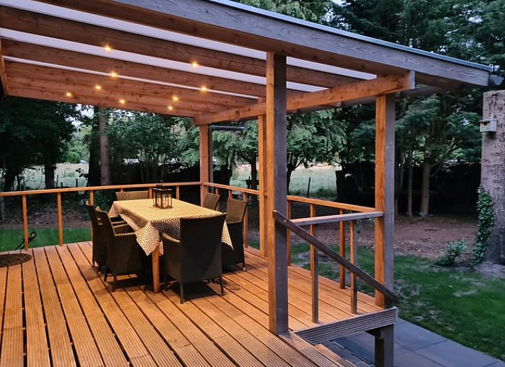 Rustic exterior of Cottage in Gasselte, Drenthe, surrounded by trees and a charming wooden fence.