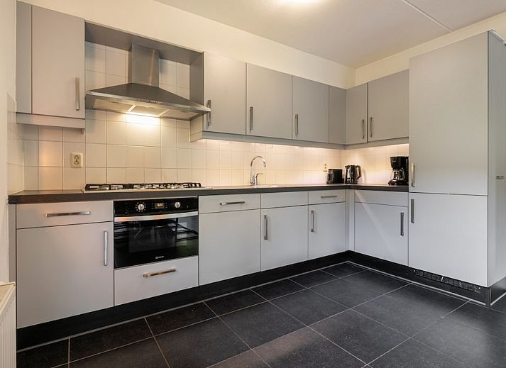 Gemuetliches Wohnzimmer der Zandduin Villa mit Sauna 10 in Hooghalen, Zentral-Drenthe, mit bequemen Sitzgelegenheiten und Blick auf die Natur.