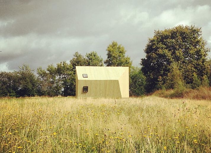 Ferienhaus in Mantinge in Drenthe, umgeben von gruenen Feldern und blauem Himmel, ideal fuer Naturliebhaber.