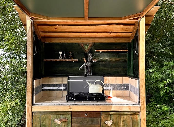 Huisje in Mantinge, vakantiehuis in Drenthe met een gezellige buitenruimte en houten zitplaats, omgeven door natuur.