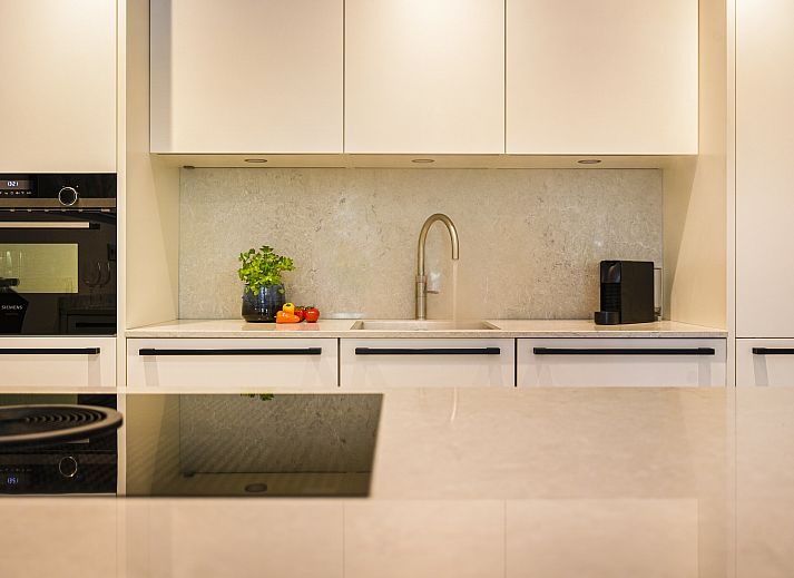 Moderne keuken in Hof van Saksen 2-persoons Wellnessboerderij, Nooitgedacht, Drenthe met eiland en stijlvolle barkrukken.