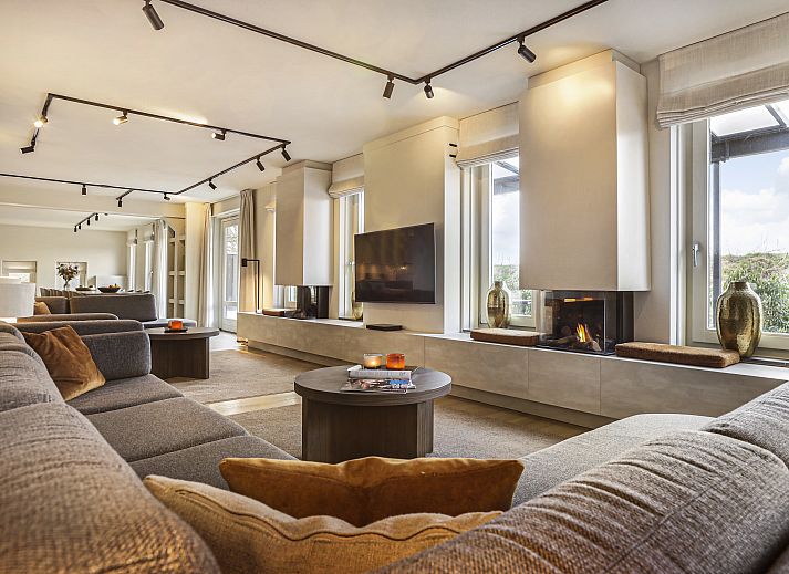 Gezellige woonkamer in Hof van Saksen 18-persoons boerderij, Nooitgedacht, Drenthe met ruime zithoek en open haard.