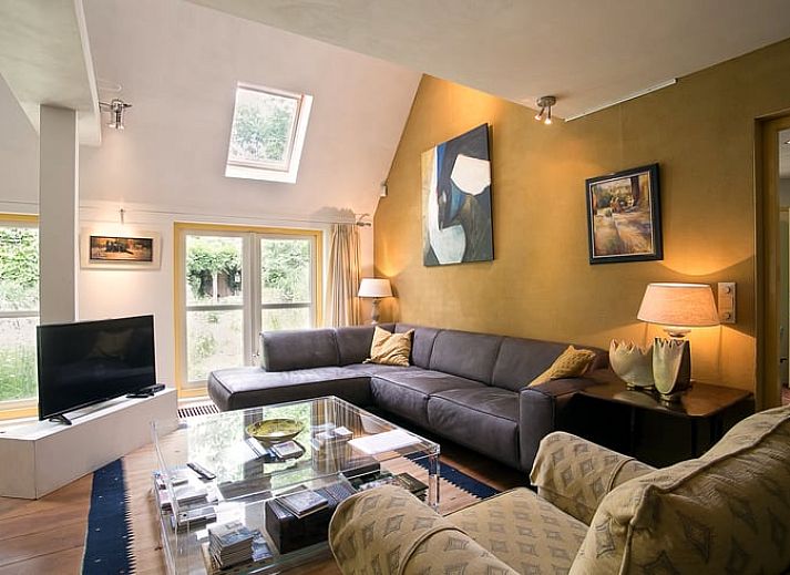 Gemuetliches Wohnzimmer im Ferienhaus in Een, Nord-Drenthe, mit bequemem Sofa und Kunst an der Wand.