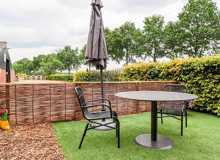 Esszimmer im Ferienhaus in Een, Nord-Drenthe, mit Blick auf den Garten und Kunst an der Wand.