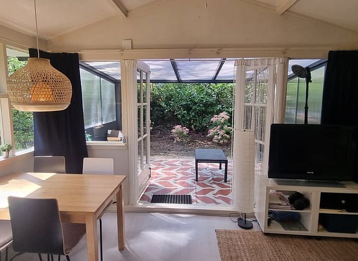 Gemuetlicher Innenbereich des Huisje in Norg, einem Ferienhaus in Norg, Nord-Drenthe, mit Blick auf die gruene Natur durch grosse Fenster.