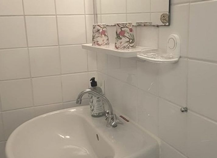 Gemuetliches Wohnzimmer im Ferienhaus in Norg, Nord-Drenthe mit bequemer Sitzecke und Blick auf die gruene Natur.