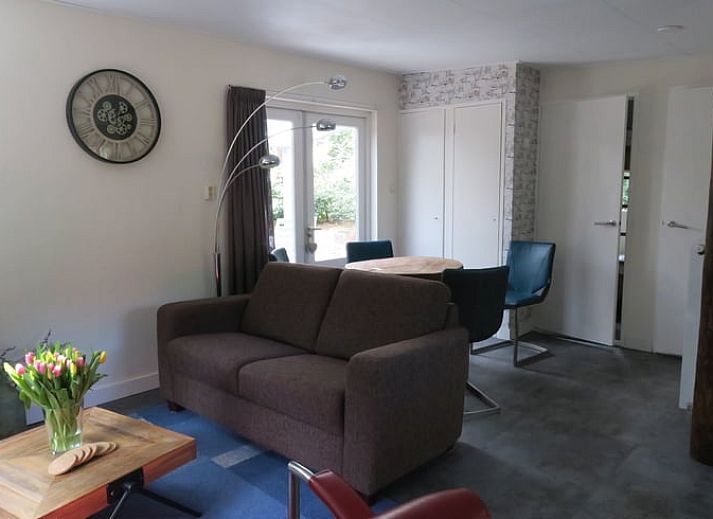 Gemuetliches Wohnzimmer von Huisje in Norg, Ferienhaus in Nord-Drenthe, mit komfortabler Sitzecke und Blick auf die Natur.