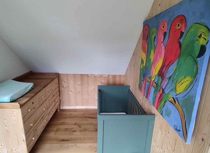 Gemuetliches Wohnzimmer des Ferienhauses DG588 in Midlaren, Drenthe, mit bunten Stuehlen und einem runden Esstisch.