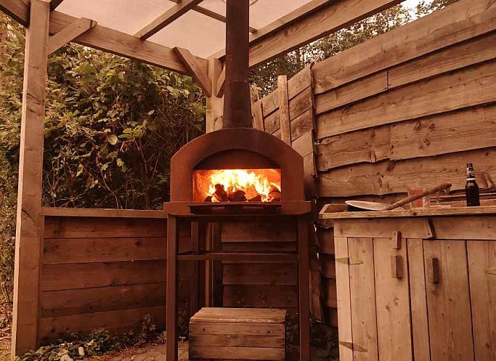 Gemuetliches Wohnzimmer des Ferienhauses DG588 in Midlaren, Drenthe, mit bunten Stuehlen und einem runden Esstisch.