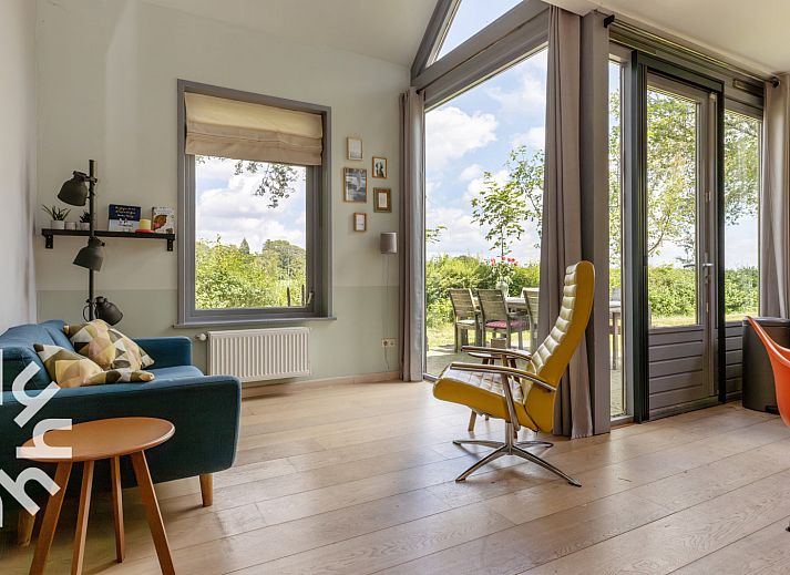Tuin van DG588 vakantiehuis in Midlaren, Drenthe, met trampoline en houten zitmeubilair onder schaduwrijke bomen.