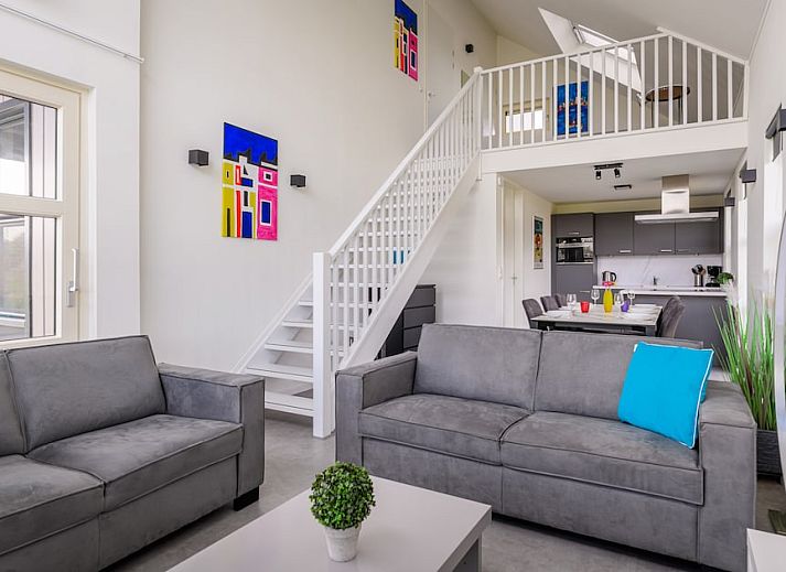 Bright living room of Drentsche E Plus bungalow in Tynaarlo, North Drenthe with modern furnishings and views of green surroundings.