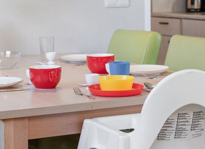 Eettafel in Het Land van Bartje 4-persoons peuterstacaravan in Ees, Drenthe met kleurrijk servies.