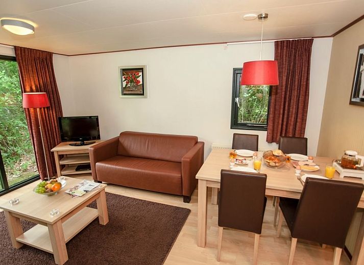 Cozy living room in Het Land van Bartje 4-person mobile home 4BCV in Ees, Drenthe, with comfortable seating area and dining table.