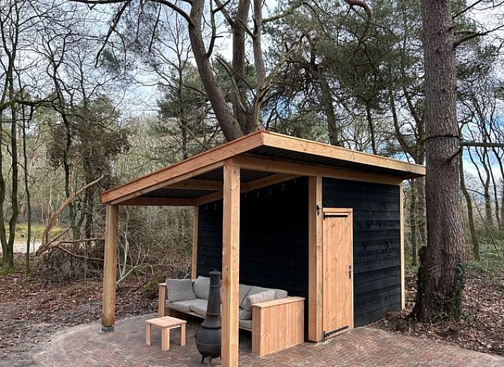 Lichte woonkamer in Huisje in Steenbergen, vakantiehuis in Drenthe met uitzicht op groene tuin en serene omgeving.