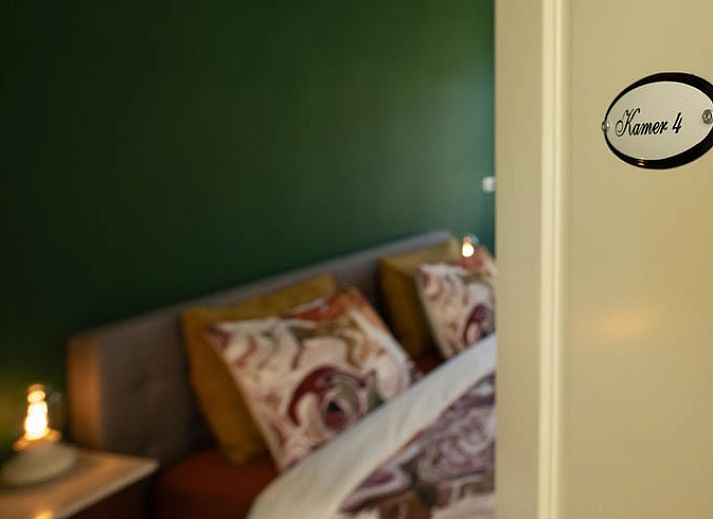Cozy bedroom in a cottage in Veenhuizen, North Drenthe, with colorful bedding and a view of the green surroundings.