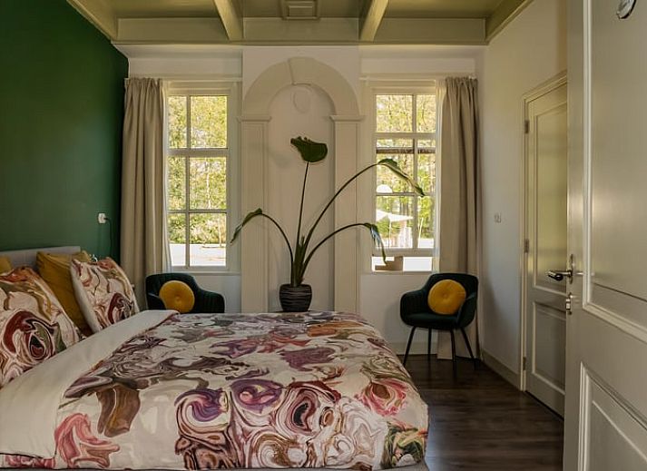 Cozy bedroom in a cottage in Veenhuizen, North Drenthe, with colorful bedding and a view of the green surroundings.