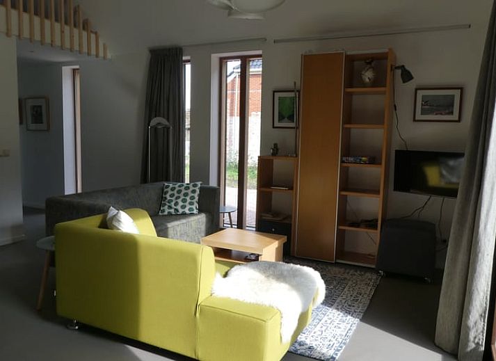 Veranda van Huisje in Bunne, vakantiehuis in Noord Drenthe, met houten terras, parasol en bloeiende geraniums, omgeven door groen landschap.