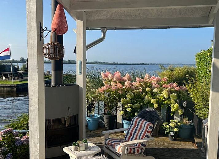 Geniessen Sie die ruhige Veranda des Huisje in Matsloot, einem Ferienhaus am Wasser in Nord-Drenthe, mit schoenem Seeblick.