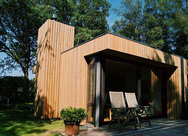 Natuerliche Umgebung des Ferienhauses DG357 in Meppen, Drenthe mit einem Grashuepfer auf einem Stuhl.