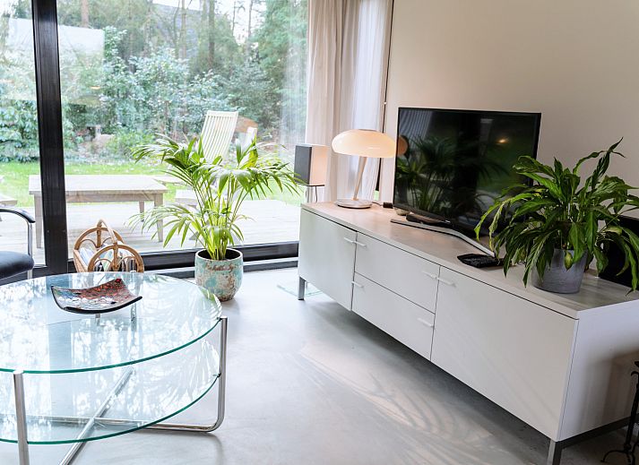 Terrasse des Ferienhauses DG357 in Meppen, Drenthe mit Holzstuehlen und gruener Umgebung.