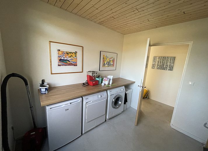 Terrasse des Ferienhauses DG357 in Meppen, Drenthe mit Holzstuehlen und gruener Umgebung.