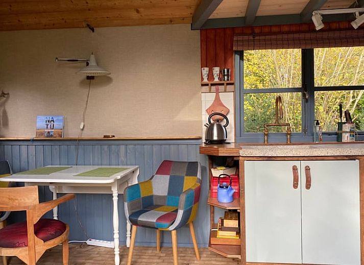 Gemuetlicher Innenbereich des Ferienhauses in Meppen mit Kaminofen und bunten Stuehlen, ideal zum Wohlfuehlen.