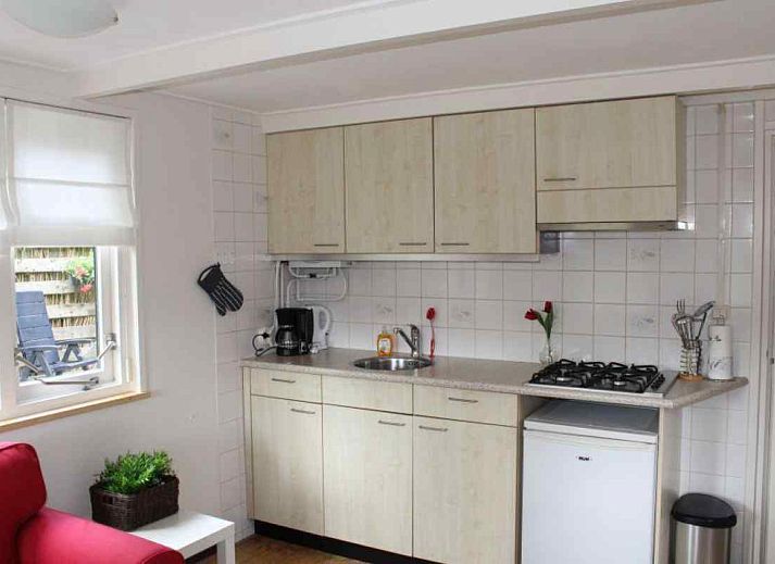 Gemuetliches Wohnzimmer im Ferienhaus DG280 in Exloo, Suedost-Drenthe, mit bequemem roten Sofa und Blick auf die gruene Natur.