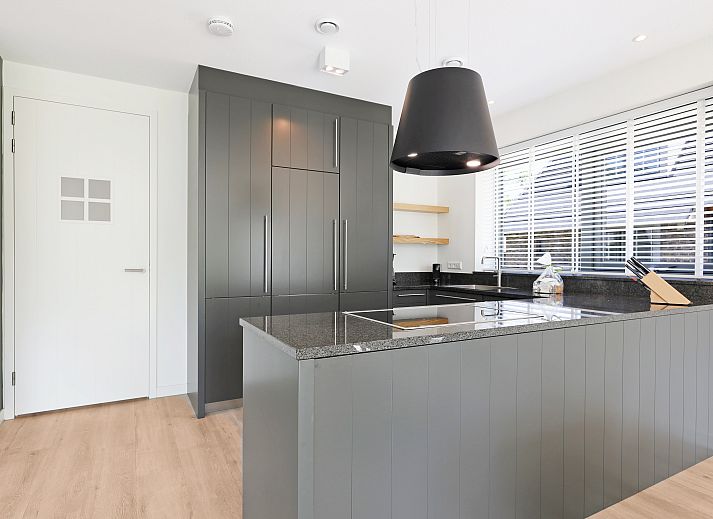 Stijlvolle woonkamer van PUUR Exloo vakantiehuis in Drenthe met groene accenten.